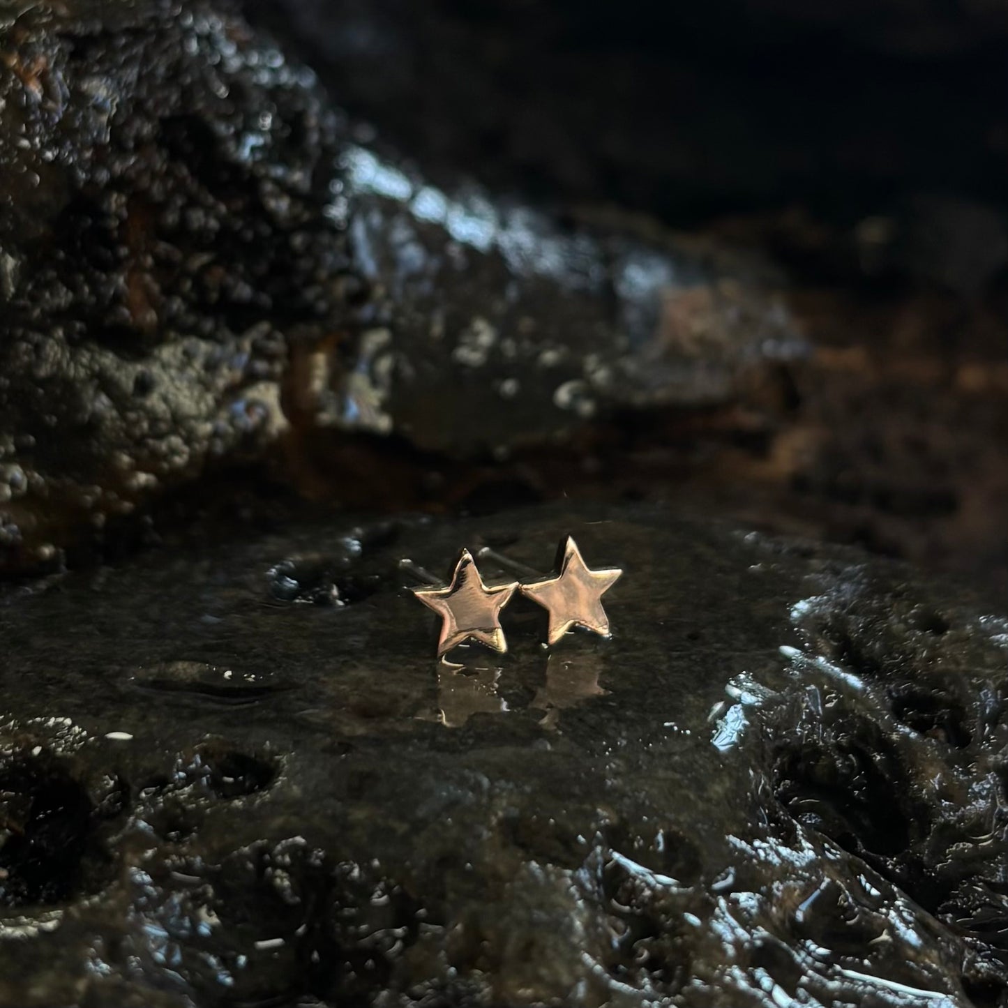 Rose gold Star-shaped earrings on a dark textured surface