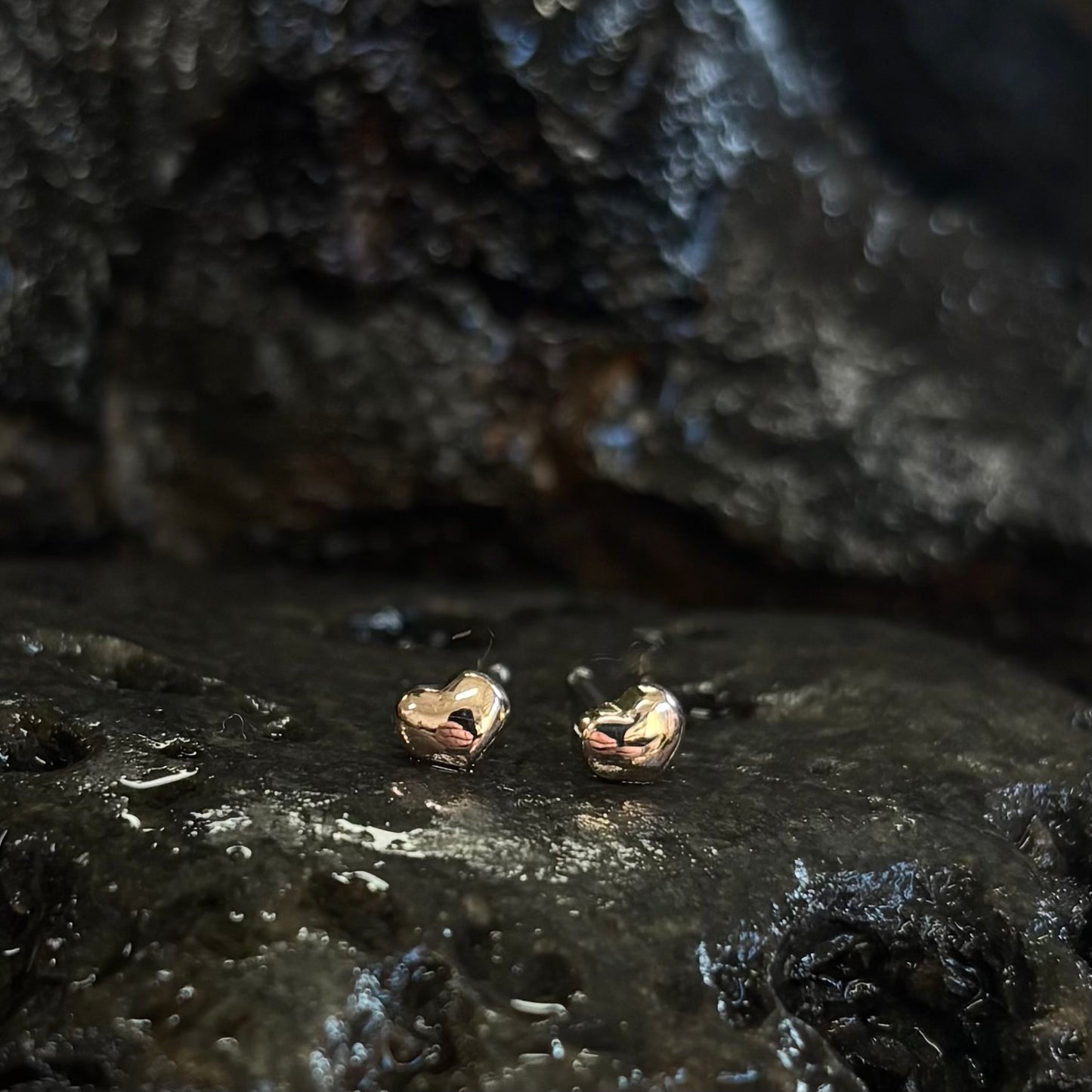 rose Gold heart-shaped earrings on a dark, textured surface