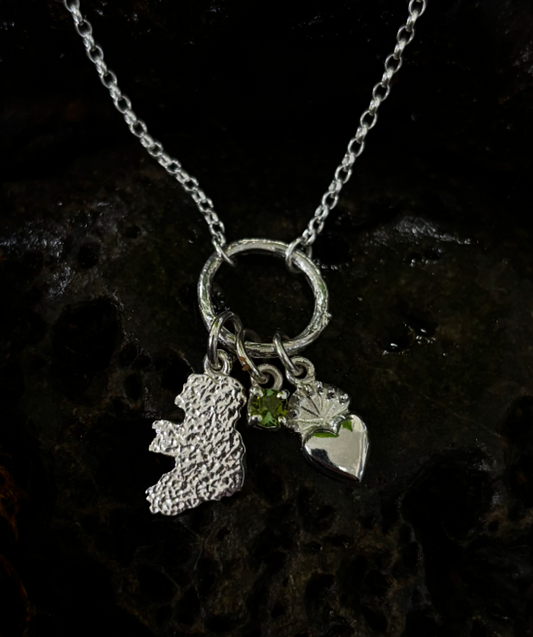 Silver necklace with three charms on a dark background