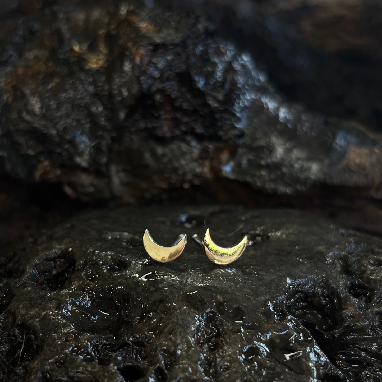 Gold crescent moon earrings on a dark textured surface