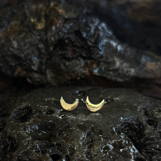 Gold crescent moon earrings on a dark textured surface