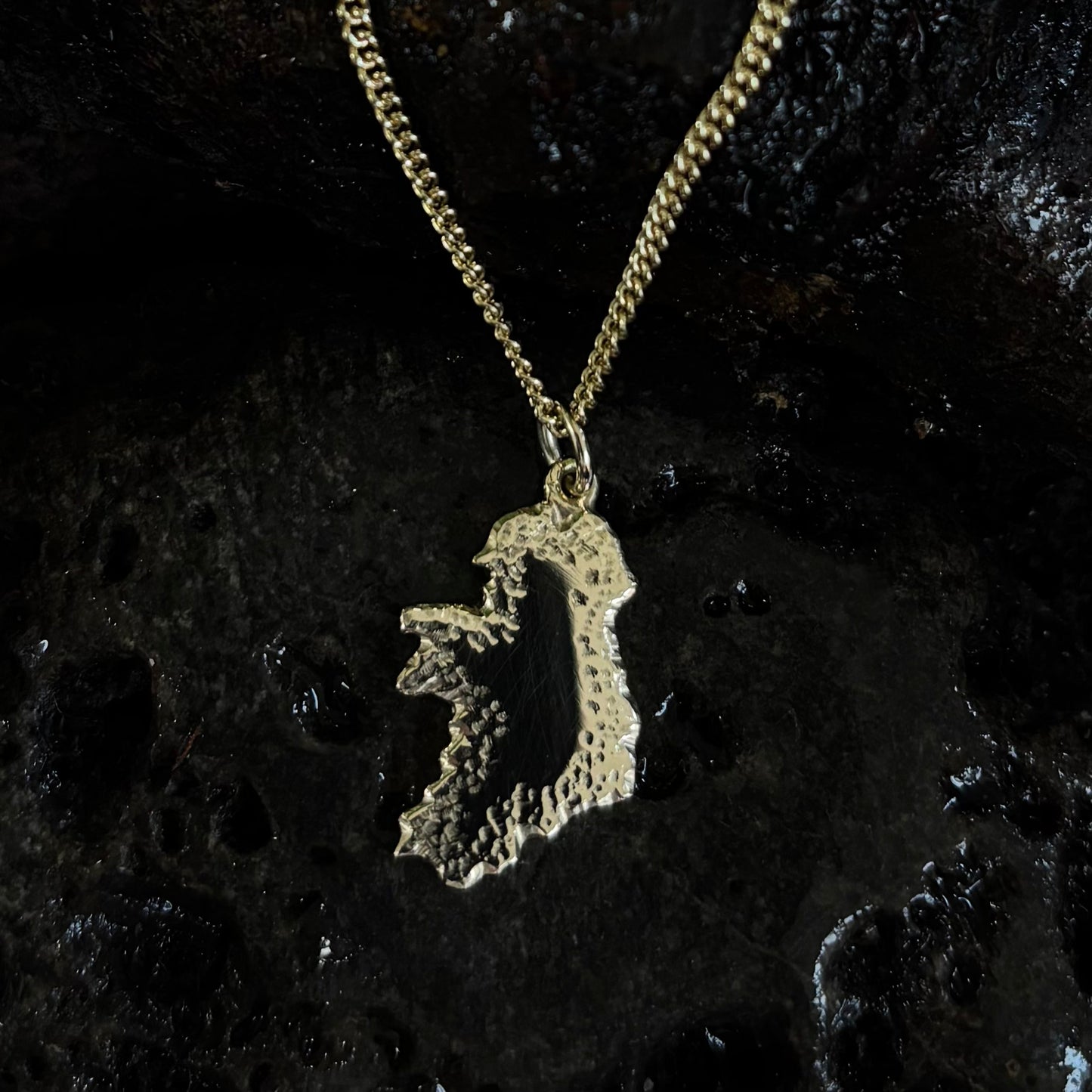 Gold Ireland necklace with a unique pendant on a dark textured background