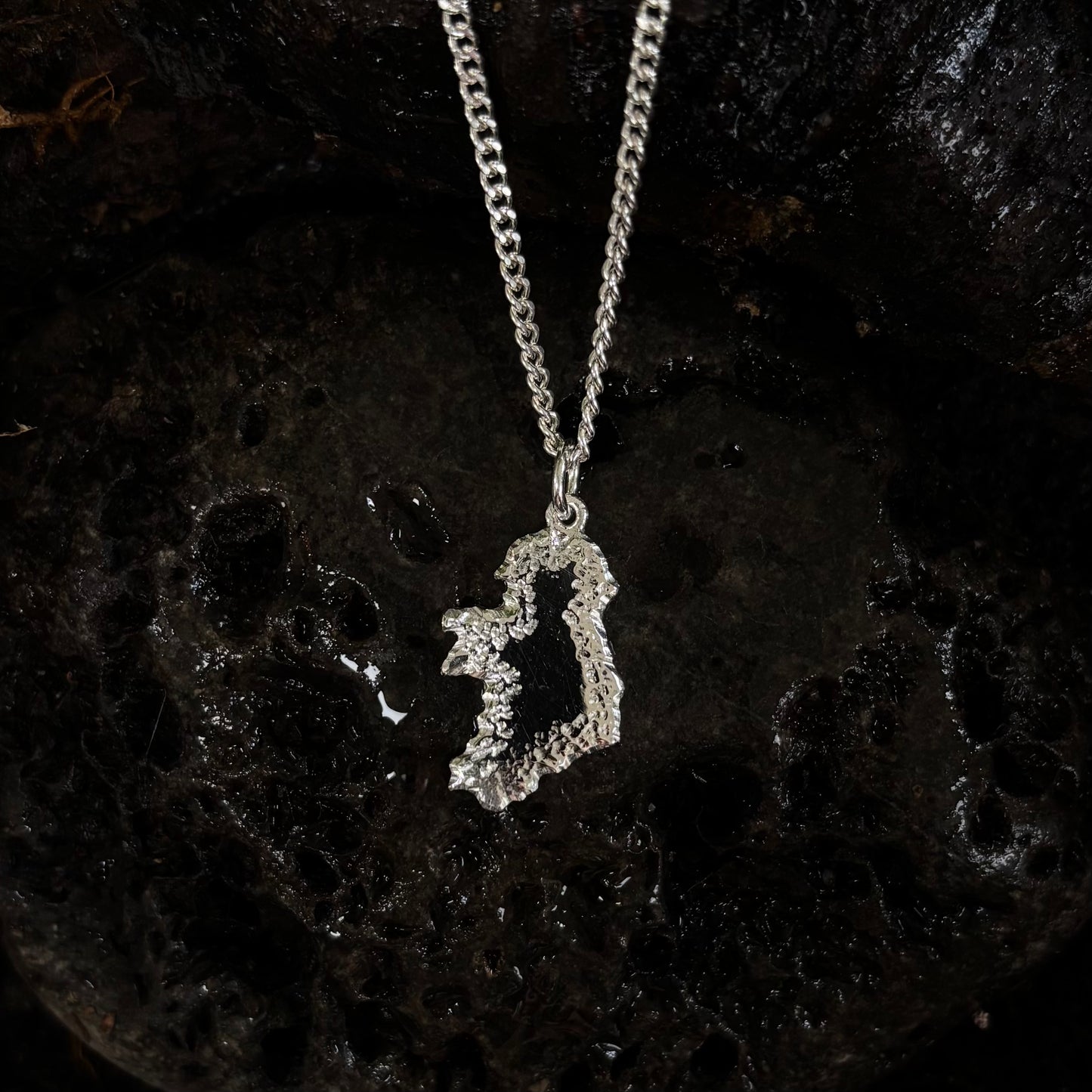 Silver Ireland shaped pendant on a dark textured background